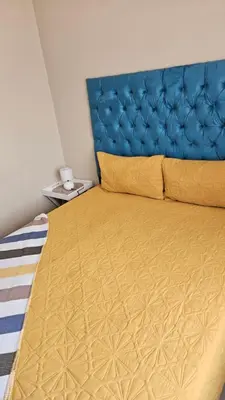 a bedroom with a yellow bed with a blue headboard at Waterfall Ridge Professional Apartment in Midrand