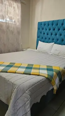 a bed with a blue headboard and a blanket on it at Waterfall Ridge Professional Apartment in Midrand
