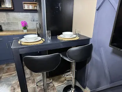 a black counter with two chairs and plates on it at Spacious stay-in 1bedroom apartment in Kempton Park