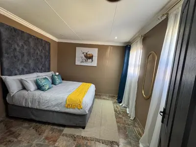 a bedroom with a bed with blue and yellow pillows at Spacious stay-in 1bedroom apartment in Kempton Park