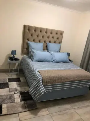 a bed with blue pillows in a room at Cosy duplex in the heart of Midrand in Midrand