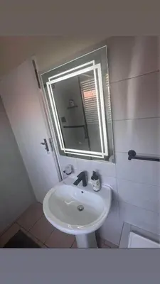 a white bathroom with a sink and a mirror at Cosy duplex in the heart of Midrand in Midrand
