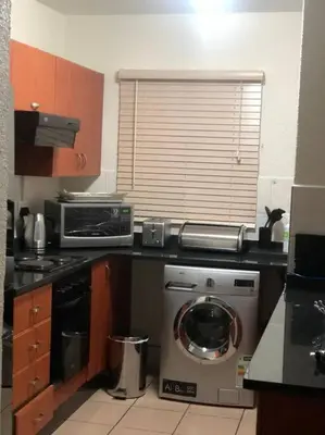 a kitchen with a washing machine and a microwave at Cosy duplex in the heart of Midrand in Midrand