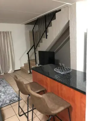 a kitchen with two chairs and a counter and a staircase at Cosy duplex in the heart of Midrand in Midrand