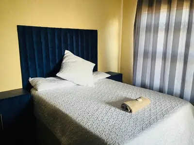 a bed with a blue headboard and a bag on it at Kanganyisa guest house in Tzaneen