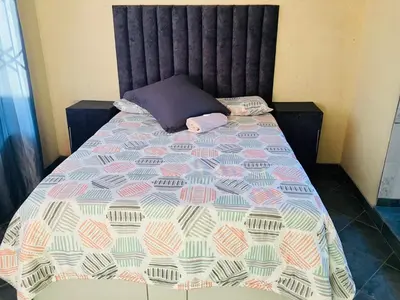 a bed with a purple pillow and a blanket at Kanganyisa guest house in Tzaneen