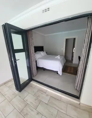 a bedroom with a bed and a large glass window at Limewood Pool view in Sandton