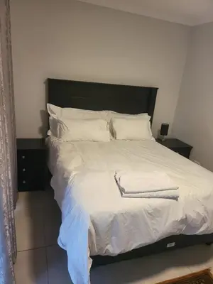 a bed with white sheets and white pillows at Limewood Pool view in Sandton