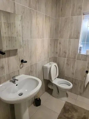 a bathroom with a white toilet and a sink at Limewood Pool view in Sandton