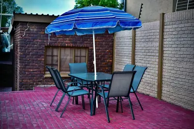 a table and chairs with a blue umbrella at SEEYAs Nest in Mataffin