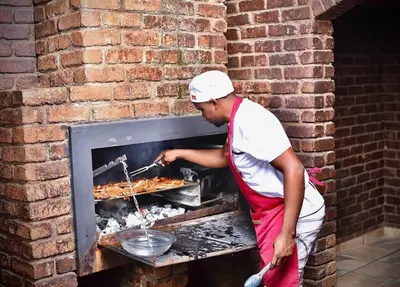 a man cooking food in a brick oven at SEEYAs Nest in Mataffin