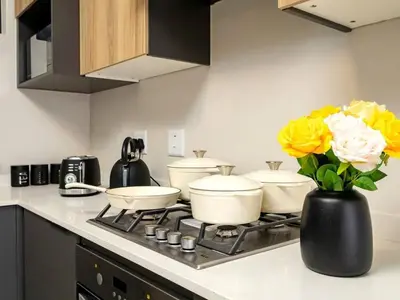 a kitchen with four pots and pans on a stove with flowers at Urban Retreat in Midrand