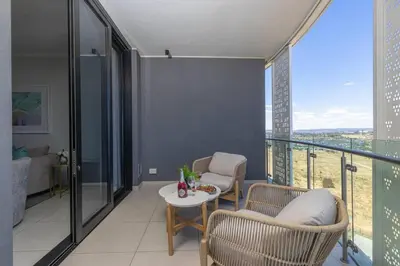 a living room with a table and chairs and a balcony at Waterfall Luxury Suites in Midrand