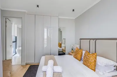 a bedroom with a large white bed with orange pillows at Waterfall Luxury Suites in Midrand