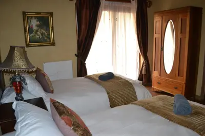 a bedroom with two beds and a window at Fox & Squirrel in Dullstroom