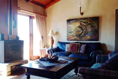 a living room with a blue couch and a table at Fox & Squirrel in Dullstroom