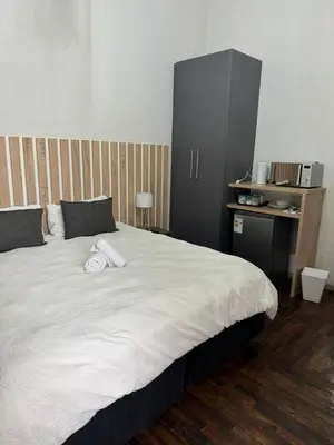 a bedroom with a large white bed with a black cabinet at Kioma Guest House in Mokopane