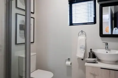 a bathroom with a sink and a toilet and a mirror at The Henlee Apartment on New - Power Backup, Gym ,Pool in Midrand