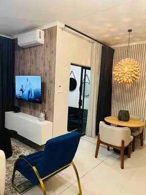 a living room with a blue chair and a table at The Henlee Apartment on New - Power Backup, Gym ,Pool in Midrand