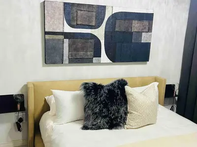 a dog sitting on top of a bed with pillows at The Henlee Apartment on New - Power Backup, Gym ,Pool in Midrand