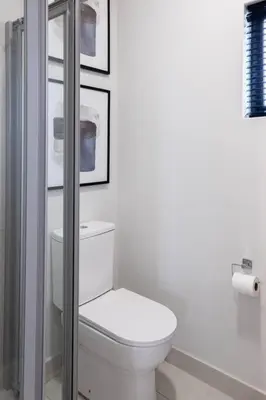 a bathroom with a toilet and some pictures on the wall at The Henlee Apartment on New - Power Backup, Gym ,Pool in Midrand