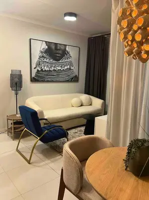 a living room with a couch and a table and chairs at The Henlee Apartment on New - Power Backup, Gym ,Pool in Midrand