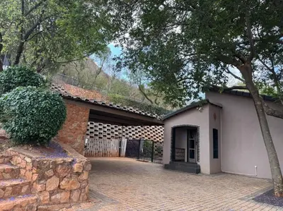 a white building with a stone wall next to a driveway at Casa Galetti in Hartbeespoort