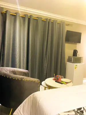 a bedroom with green curtains and a table and a bed at Kwena Guesthouse in Groblersdal