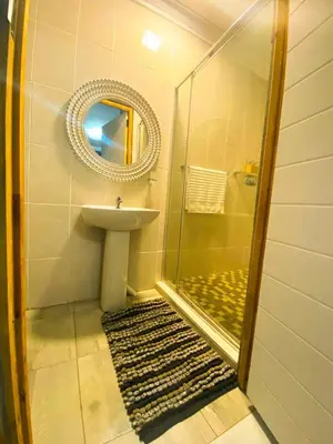 a bathroom with a sink and a shower with a mirror at Kwena Guesthouse in Groblersdal