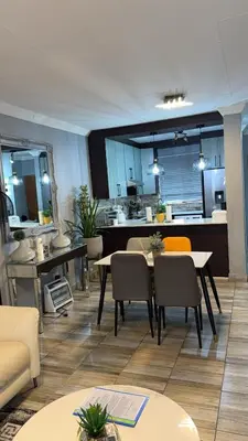 a living room with a table and chairs and a kitchen at Luxuriously finished 2 bedroom in Midrand