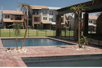 a swimming pool with two palm trees next to a fence at Luxuriously finished 2 bedroom in Midrand