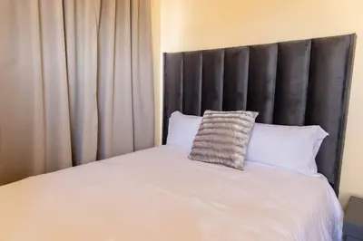 a bed with a black headboard and white pillows at Pristine in Centurion