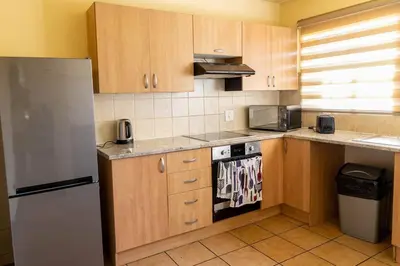 a kitchen with wooden cabinets and a stainless steel refrigerator at Pristine in Centurion