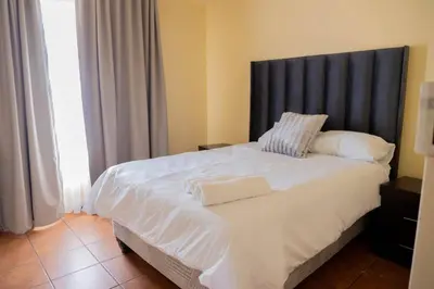 a bedroom with a large white bed with a black headboard at Pristine in Centurion