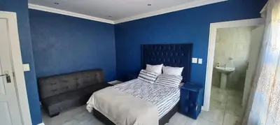 a blue bedroom with a bed and a sink at Budais guest lodge in Kempton Park