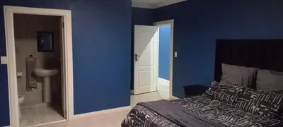 a bedroom with blue walls and a bed and a bathroom at Budais guest lodge in Kempton Park