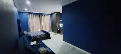 a blue room with a bed and a blue wall at Budais guest lodge in Kempton Park