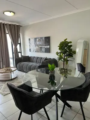 a living room with a glass table and black chairs at Cozy home at The Blyde in Pretoria