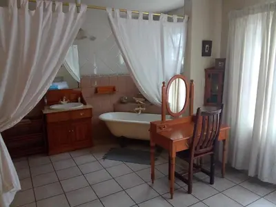 a bathroom with a tub and a sink and a mirror at Villa La Corrie GUEST LODGE in Steelpoort