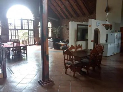 a dining room with a table and chairs and a kitchen at Villa La Corrie GUEST LODGE in Steelpoort