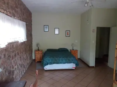 a bedroom with a bed and a stone wall at Villa La Corrie GUEST LODGE in Steelpoort