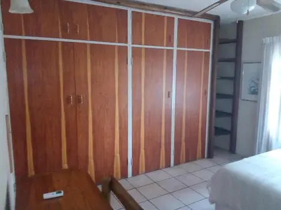 a bedroom with wooden doors and a bed and a table at Villa La Corrie GUEST LODGE in Steelpoort