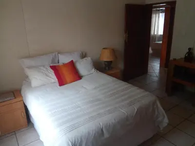 a bedroom with a white bed with a red pillow at Villa La Corrie GUEST LODGE in Steelpoort