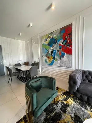 a living room with a green chair and a table at El Mayor Deluxe Suite MENLYN MAINE in Pretoria