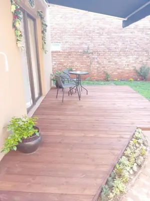 a wooden deck with a table and chairs on it at Hoovers Nest in Pretoria