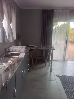 a kitchen with a sink and a table and a window at Hoovers Nest in Pretoria