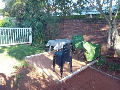 a table with a green cover and two chairs on a deck at Hoovers Nest in Pretoria