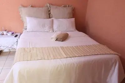 a white bed with a towel on top of it at Thenjwas Sleep-Over Lodge in Nelspruit