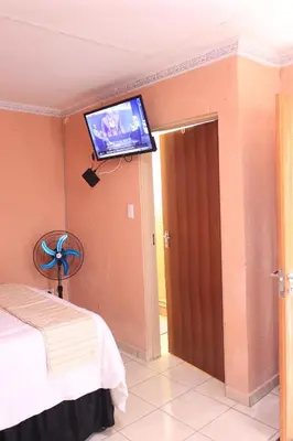 a room with a bed and a tv on the wall at Thenjwas Sleep-Over Lodge in Nelspruit