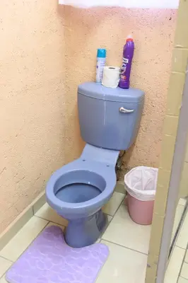 a bathroom with a blue toilet in a room at Thenjwas Sleep-Over Lodge in Nelspruit